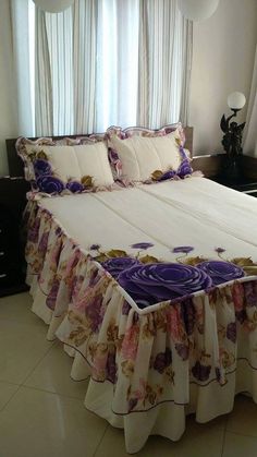 a bed with purple and white bedspread in front of two windows next to each other