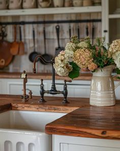 a vase with flowers sitting on top of a wooden counter next to a kitchen sink