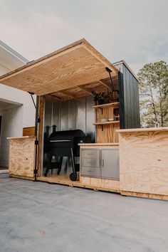 an outdoor bbq is built into the side of a building with wood siding and metal doors