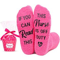 two pink socks with sayings on them next to a gift bag