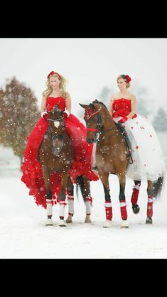 two women in red dresses riding horses through the snow with one woman dressed as santa claus