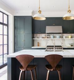 three stools sit in front of an island with marble countertops and stainless steel appliances