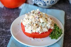 a white plate topped with a tomato covered in feta cheese and garnished with parsley