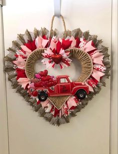 a heart shaped wreath with a red truck and bow hanging on the front door,