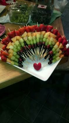 a platter filled with fruit and skewers on top of a wooden table