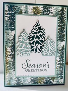 a christmas card with pine trees and the words season's greetings on it