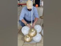 a man is decorating some balloons with gold and white colors on the floor in front of him