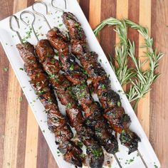 skewers of meat and herbs on a white plate