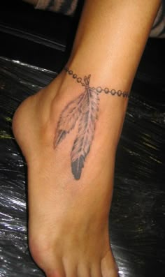 a person with a tattoo on their foot that has a cross and a feather attached to it