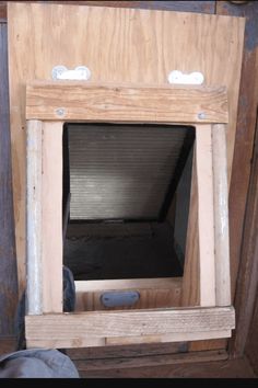 an open window in the side of a wooden wall with no glass on it, and someone's feet standing next to it