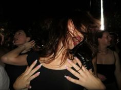 a woman with her hands on her chest in front of other people at a party