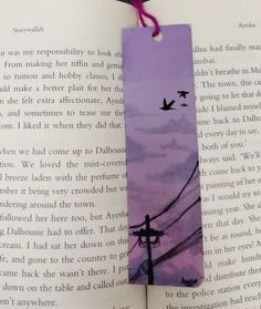 a bookmark with birds flying in the sky on top of an open book page