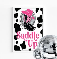 a disco ball and poster with the words saddle up on it, against a white background