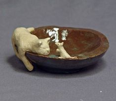 a small ceramic cat and kitten in a bowl