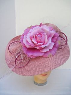 "* This design features a sophisticated fold with the same braiding as the hat foundation folded into design loops. The addition of the large variegated Rose, millinery netting and delicate fuzzy sticks creates the drama. * The hat form is 12\" in diameter and has been designed with a tilt. * It is light weight, balanced and comfortable to wear year round. * The large metal clip on the inside allows it to be in any desired position. * Wear it throughout the year for special events including all Elegant Rose Fascinator With Handmade Flowers, Elegant Rose Fascinator For Kentucky Derby, Elegant Rose Hat For Kentucky Derby, Hat Form, Tiki Dress, Design Loop, Ladies Luncheon, Round Hat, Church Ceremony