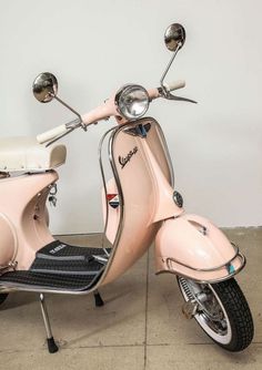 a pink scooter is parked in front of a white wall