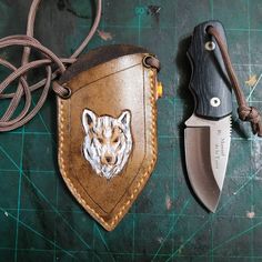 a leather sheath with a wolf head on it next to a knife