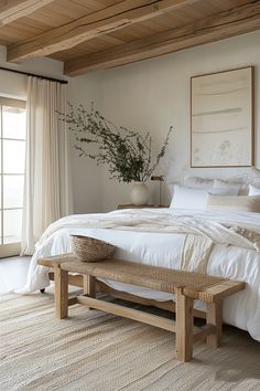 a bed with white linens and pillows in a bedroom next to a large window