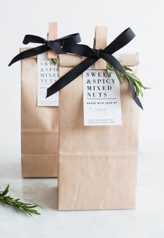 two brown paper bags with black ribbon tied around the handles and one bag has an ad for sweet naked nibs on it