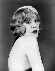 an old black and white photo of a woman wearing a headband with her hands on her hips