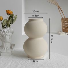 a white vase sitting on top of a table next to a flower pot