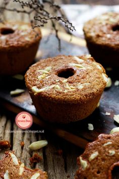 several muffins on a wooden table with some nuts scattered around the muffin