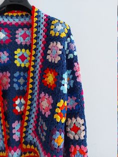 a colorful crocheted jacket hanging on a wall