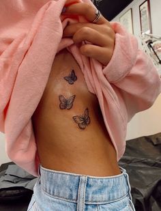 a woman's stomach with three butterflies on her side and the back of her body