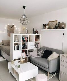 a living room filled with furniture next to a white table and bookshelf on top of a hard wood floor