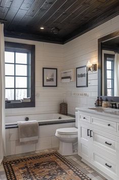 a bathroom with a rug, sink, toilet and bathtub in the middle of it