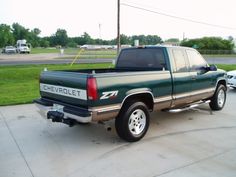 a green pick up truck parked in a parking lot