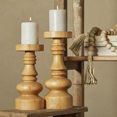 two white candles are sitting on a wooden table