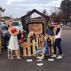 some people are standing in front of a truck with items on it and one person is holding a baseball bat