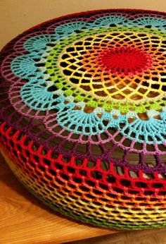 a multicolored crocheted poufce sits on top of a wooden table