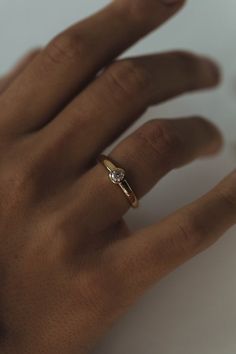 a person's hand with a diamond ring on top of their left hand, against a white background