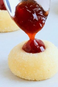 someone is pouring sauce on top of some sugary donuts that are sitting on a table