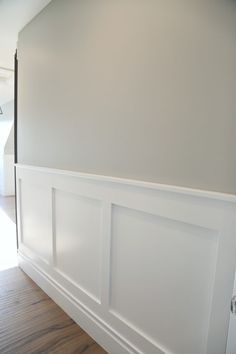 an empty room with white paneling and wood flooring on the side of the wall