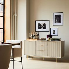 a dining room table with chairs and pictures on the wall