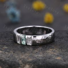 a wedding band that has been made with white gold and green stones