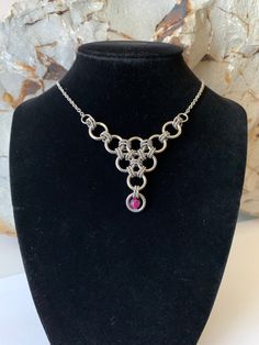 An unusual and lovely chainmail pendant made with stainless steel 'rope' rings with a Violet Dragon Vein Agate bead.  The smaller stainless steel rope rings connect the larger round wire rings, creating this triangular shaped pendant.  The necklace is a fine, 50cm stainless steel cable chain that connects at each side of the pendant. It has a stainless steel lobster clasp.  Pendant size: L: 4.5cm x W: 8.2cm This is my own original design. Stainless Steel Jewelry Making Jump Rings, Handmade Stainless Steel Pendant Chain Necklace, Violet Dragon, Chainmaille Jewelry Patterns, Chainmail Jewelry, Jewerly Beads, Dragon Vein Agate, Chain Maille Jewelry, Chain Mail