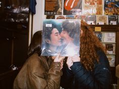 two women kissing each other in front of a poster