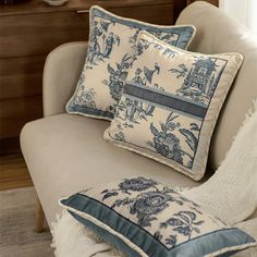 two blue and white pillows sitting on top of a couch