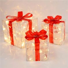 three wrapped presents with red ribbon and lights