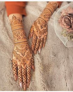 two hands with henna tattoos on them and a rose in the corner next to it