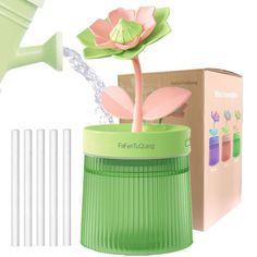 a green watering can with four white straws next to it and a pink flower