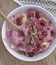 a bowl filled with ice cream and raspberries on top of a wooden table