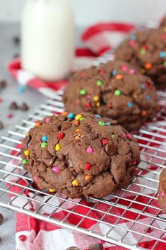 chocolate cookies with sprinkles on a cooling rack next to a glass of milk