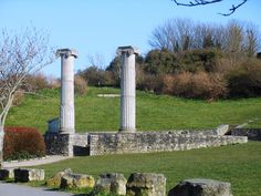 two stone pillars sitting on top of a lush green field