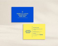 a blue and yellow business card sitting on top of a white table next to an envelope