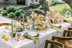 the table is set with flowers and candles for an outdoor dinner party in the backyard